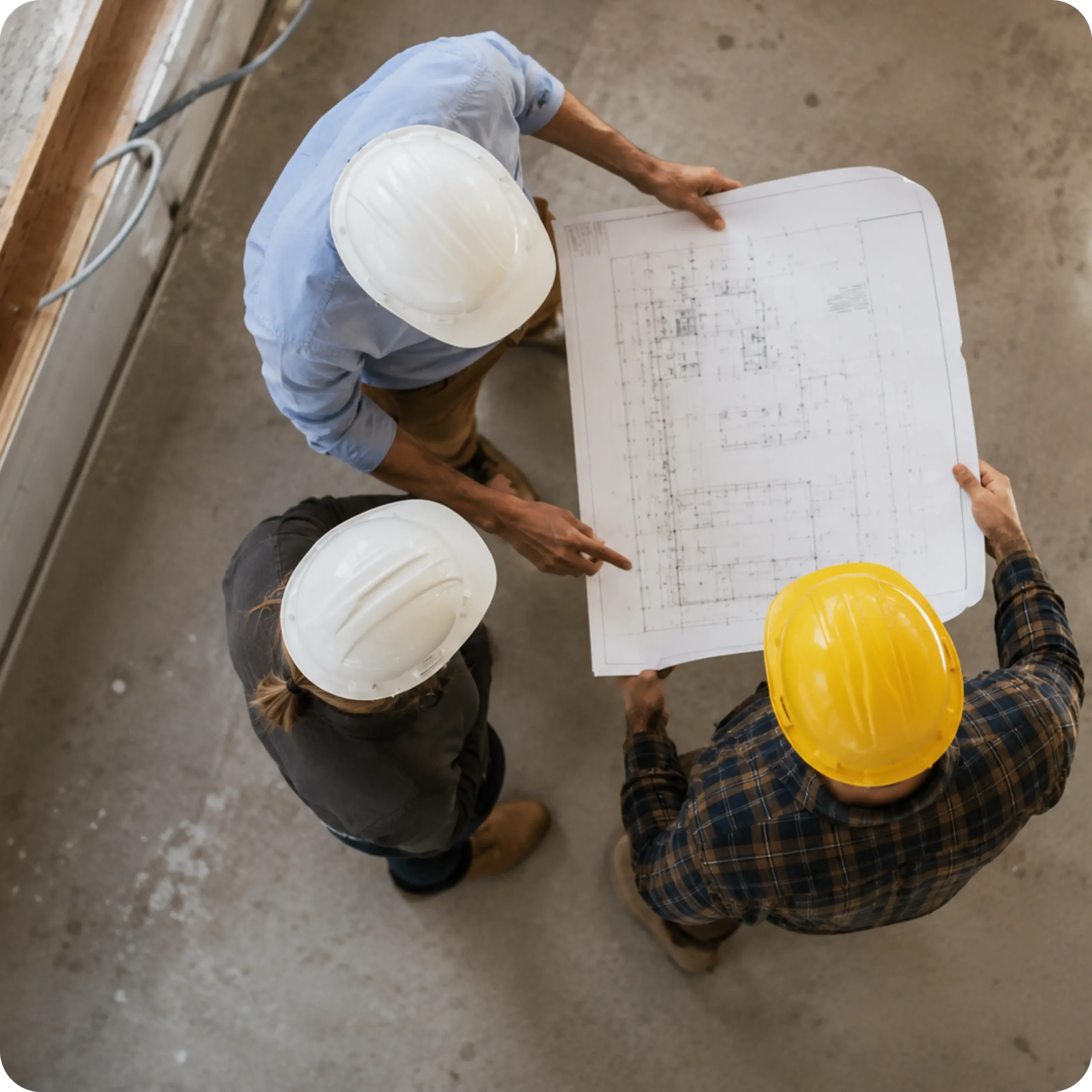 fachbauleitung3 Drei Bauleute mit Schutzhelmen besprechen einen Bauplan